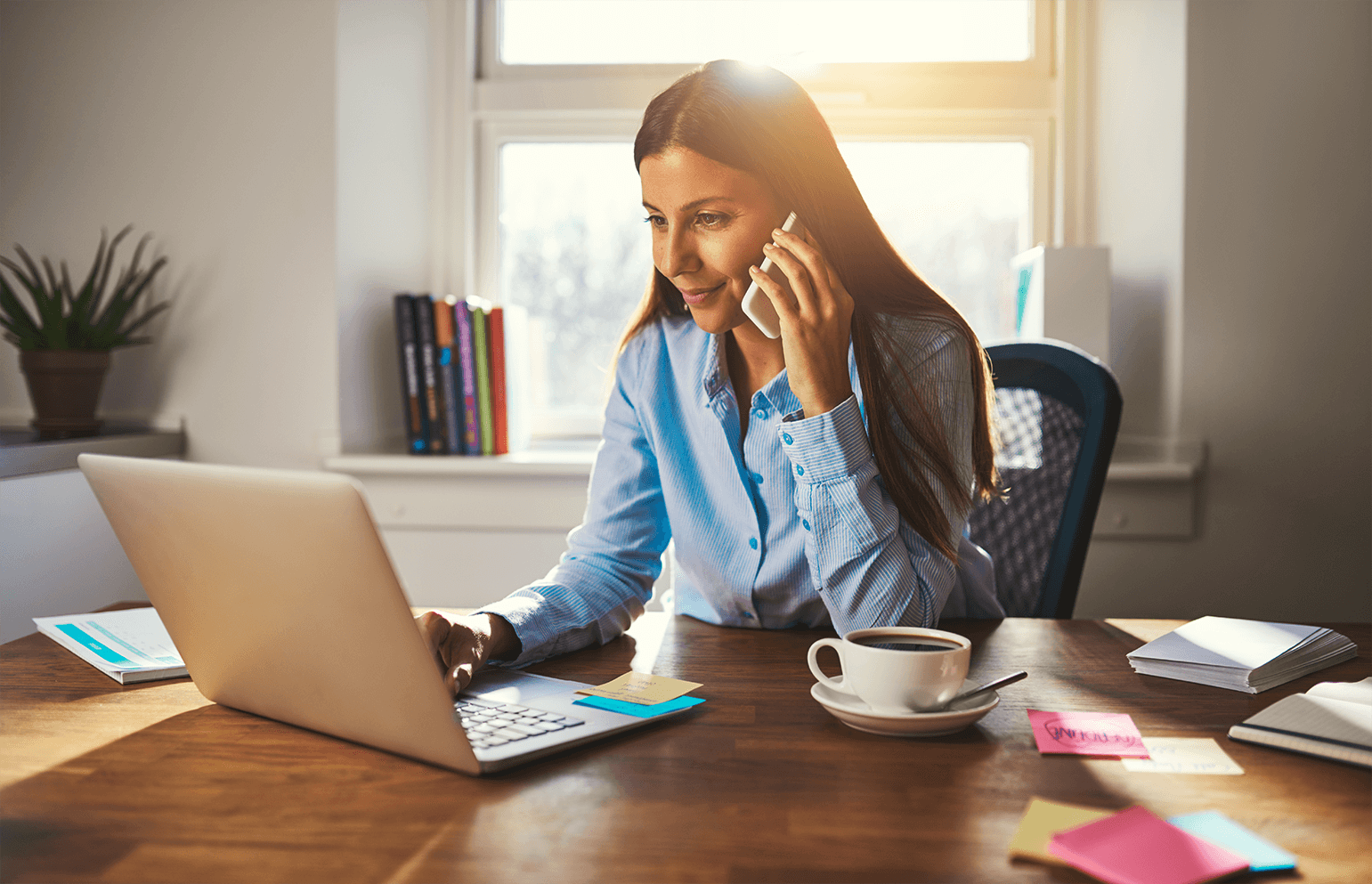 woman on the phone and working on laptop from home office