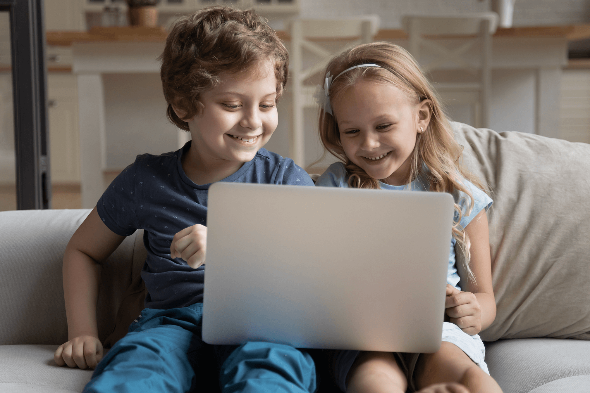2 kids sharing a computer on a couch