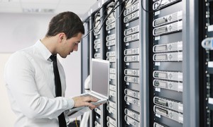 man checking a server room with laptop