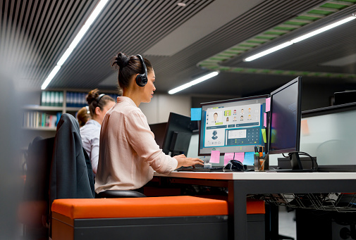 Group of customer service representatives working at a call center using headsets and their computers.