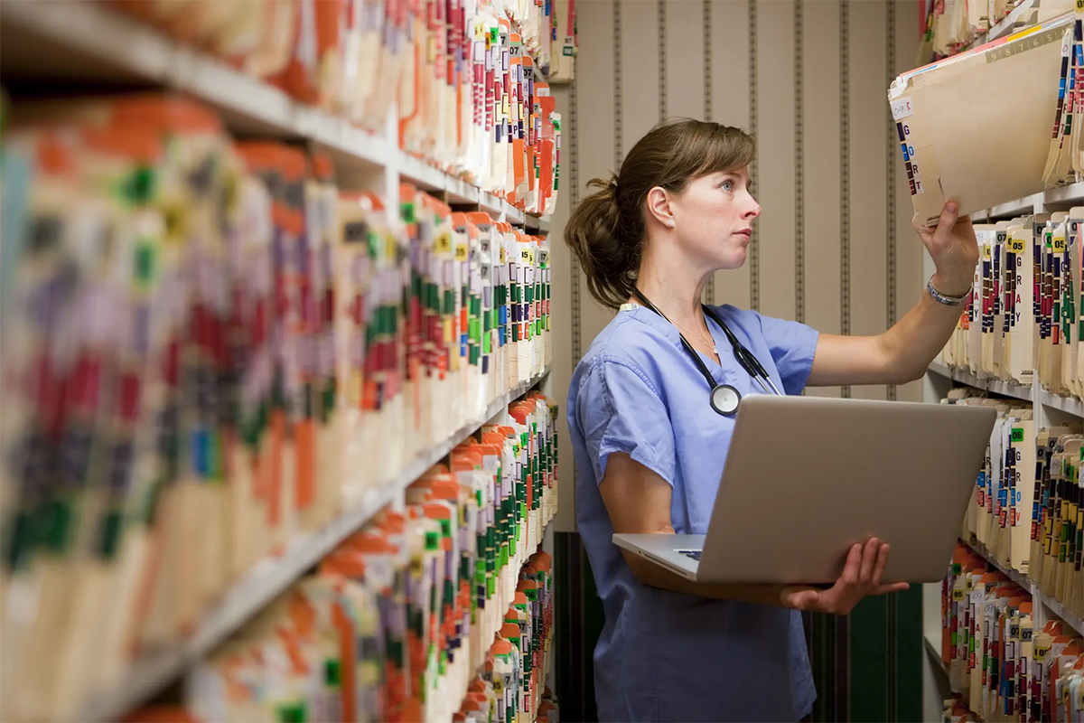 Image of a healthcare worker in a long hallway of files